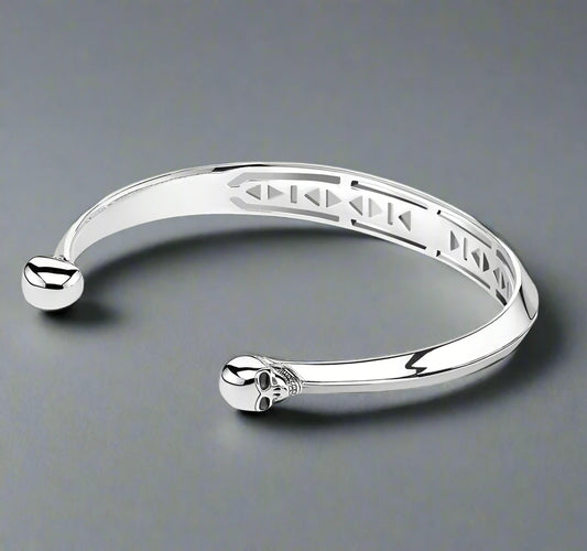 a silver skull bracelet featuring a sull at either end of the solid bracelet